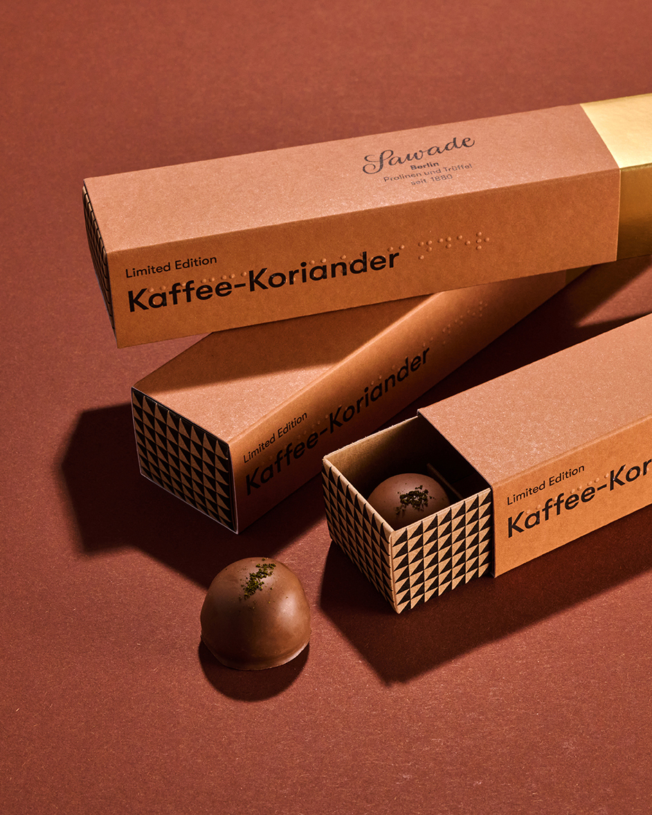 Stimmungsbild: Kaffee-Koriander Praline mit Pralinenstangen auf braunem Hintergrund